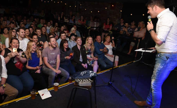 this image shows a comedian and the audience in a comedy club